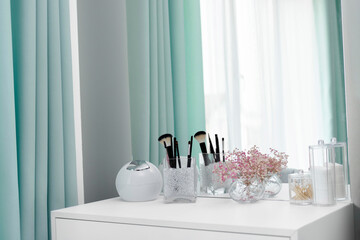Makeup brushes are in a standing vase on a dressing table. The design of the dressing table is in an elegant modern bedroom. Makeup corner in the bedroom. Interior Minimalist Design