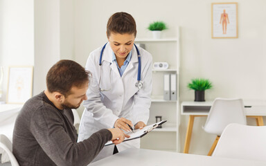 Female doctor consulting male patient in clinic showing, sharing good lab results, checking paper...