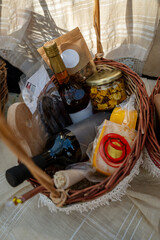 Wicker basket with a bottle of wine and gift boxes on the table