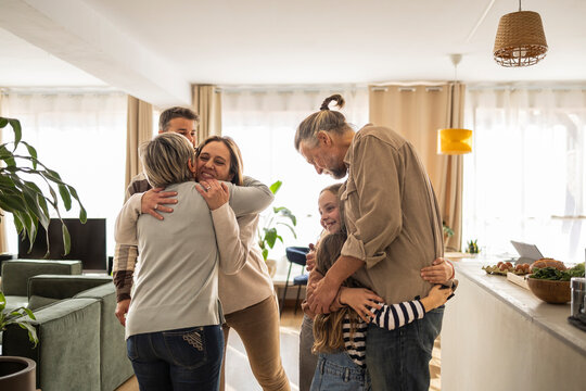 Three-generation family hugging in a cozy living room