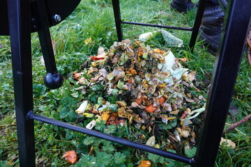 Compost bin holding fresh vegetable kitchen waste on grass