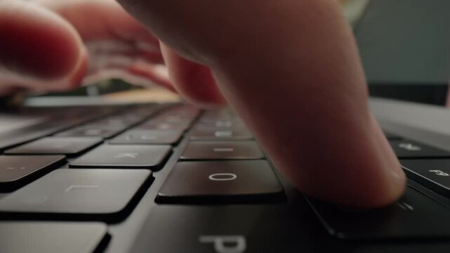 Close-up of mans fingers typing on laptop keyboard in modern caf&eacute;