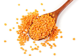 A handful of red lentils lies in a brown wooden spoon on a white insulated background.