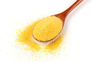 A handful of yellow corn groats (polenta) in a brown wooden spoon in close-up on a white insulated background.