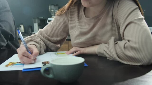 Woman completes form detailing coffee preferences. Female coffee shop employee takes test to enhance qualifications near cup of cofee slow motion
