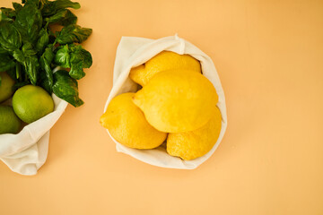 Colorful fruits and herbs are arranged in reusable cloth bags on a pastel background, highlighting the importance of eco-friendly grocery shopping and healthy eating habits.