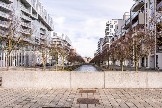 Urban pedestrian axis flanked by residential buildings in Copenhagen, minimalist and symmetrical perspective with trees and clean pavement for architectural concepts.