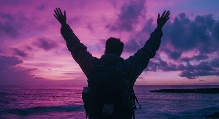 Fototapeta premium A man who embodies happiness and success is captured with his arms raised in triumph on a beach as the sun sets behind him, symbolizing mental well-being, achievement, joy, and exploration