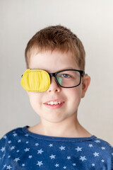 portrait of a little boy wearing glasses with an occluder to correct his vision