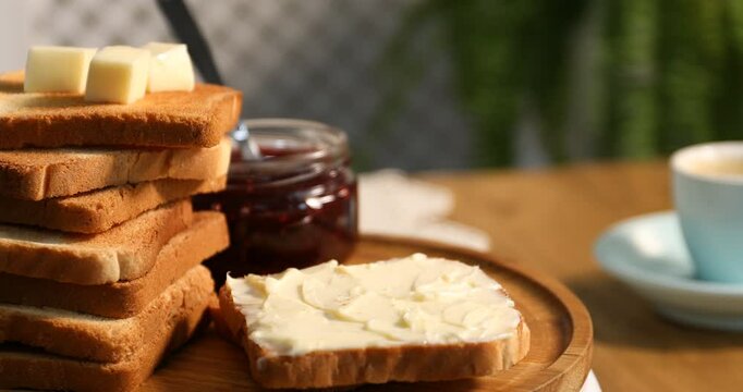 Tasty toasted bread with butter and jam on table, rotating