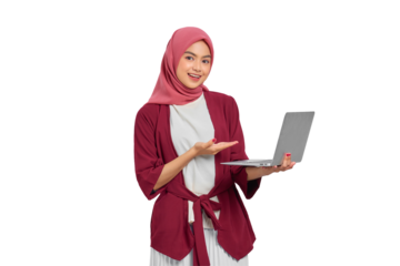 Confident young Asian Muslim woman in hijab smiling and presenting a laptop isolated on transparent background