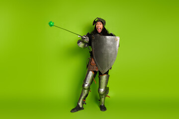 Medieval knight in full armor holding a mace and shield, standing against a bright green background...