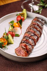 Portion of grilled sliced beef steak with vegetable garnish