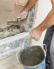 Dirty craftsman hand puts cement or plaster with trowel on a wall, closeup. Construction detail