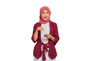 Excited young Asian Muslim woman in hijab pointing at smartphone with surprised expression isolated on transparent background