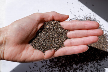 organic chia seeds in the palm of a woman, supporting heart health and digestion due to their nutritional properties. concept of wellness, dietetics, superfoods.