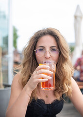 entspannte junge Frau mit Brille trinkt Alkohol