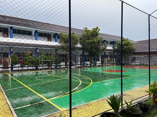 Fototapeta premium Football Field on Campus After Rain with Buildings and Trees in the Background
