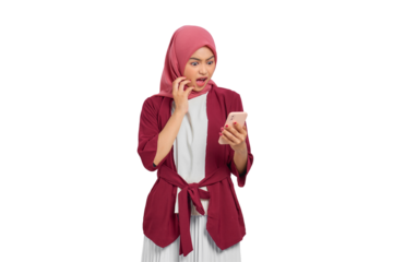 Shocked young Asian Muslim woman in hijab looking at smartphone with surprised expression isolated on transparent background