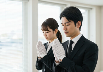 白手袋で合掌する男女の葬儀スタッフ
