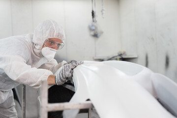 Obraz premium Auto spare parts. Painting car parts. Metal part of frame car. Automotive paint services in chamber room. Mechanic prepares to paint car frame in paint room