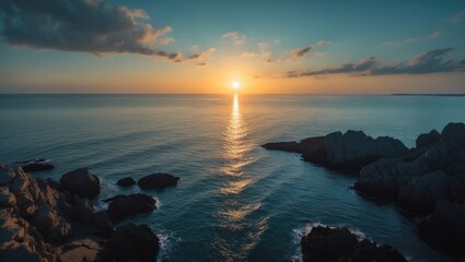 Naklejka premium A romantic aerial perspective of a sunset over the sea with dark shadows on the rocks