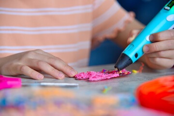 Girl hands creating plastic 3D model with 3d pen