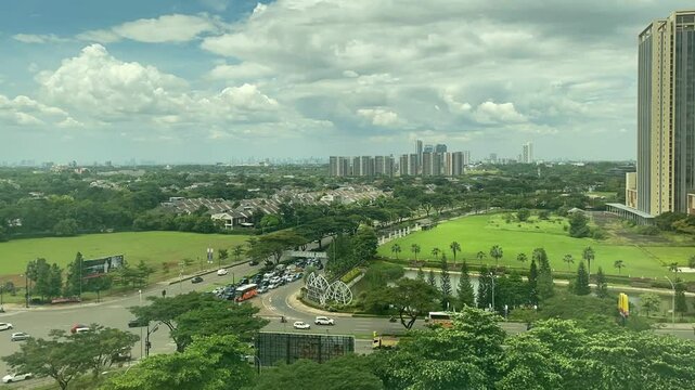 Aerial time-lapse video of BSD City featuring modern architecture, lush green parks, residential zones, and road traffic under a dramatic sky.