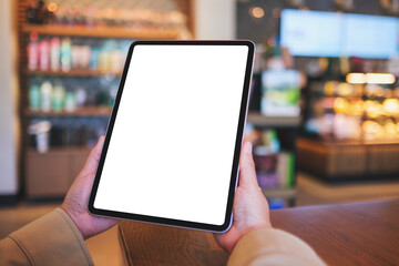 Mockup image of a woman holding digital tablet with blank white desktop screen in cafe