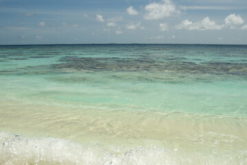 Tranquil turquoise waters and white sandy shore under a clear sky in the Maldives 