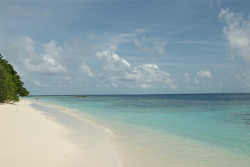 Pristine tropical beach with turquoise waters and white sand under blue sky in the Maldives 