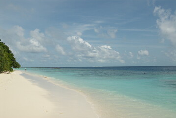 Serene tropical beach with clear blue water and white sand shoreline in the Maldives 