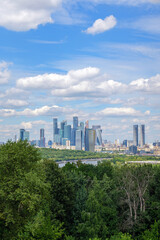 Obraz premium Scenic view from Vorobyovy Gory over Moscow River, lush green trees, and clouds in the blue sky. The natural beauty of Moscow River complements the city skyline in the background