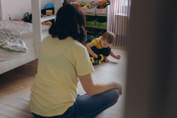 Mother and her two year old son playing in a children room, symbolizing motherhood and care