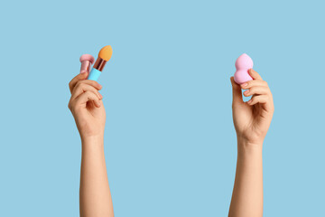 Female hands with different makeup sponges on blue background
