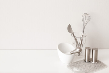 Kitchen utensils on table near white wall
