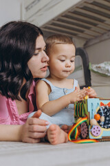 Mother and her two year old son playing in a children room, symbolizing motherhood and care