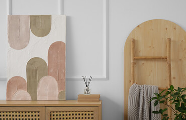 Wooden dresser and beautiful picture on white wall in room