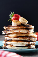 Pancakes with chocolate and fruit on wooden table