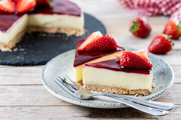 Slice of cheesecake with strawberries on wooden table