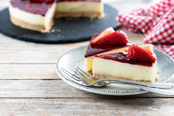 Slice of cheesecake with strawberries on wooden table. Copy space