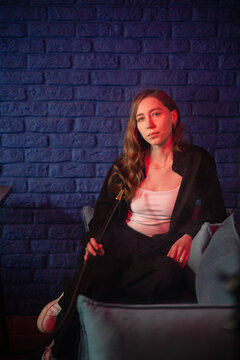 Woman Enjoying Hookah in Lounge with Colorful Lighting