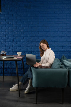 Woman Working on Laptop in Cozy Blue Cafe with Tea