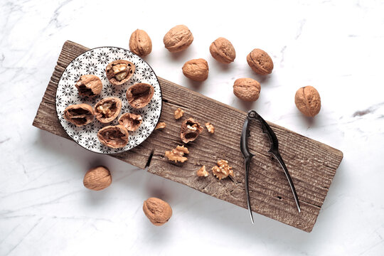 Whole and cracked walnut arrangement on rustic wooden board