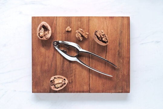 Walnut halves and nutcracker on a wooden cutting board