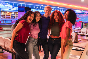 Group of diverse friends enjoying time together, embracing and smiling in a vibrant bowling alley