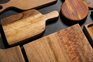 Different wooden cutting boards on black background, closeup