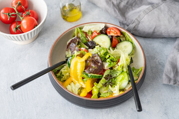 Fresh vegetable salad with feta cheese and olives on plate on a light background.