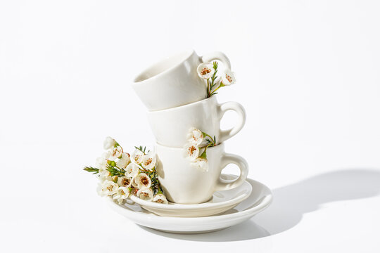 Stacked white cups with spring flowers on a white background
