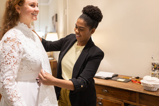 Tailor fitting lace bridal dress in elegant atelier setting